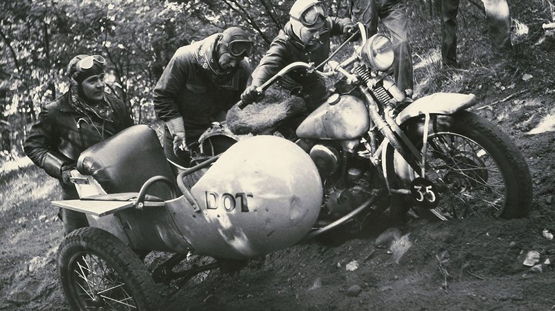骑士推摩托车出排水沟的档案照片。